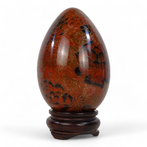 334 - A 20th century cloisonne egg - intensely decorated with flowers, raised on a hardwood stand, 20cm hi... 