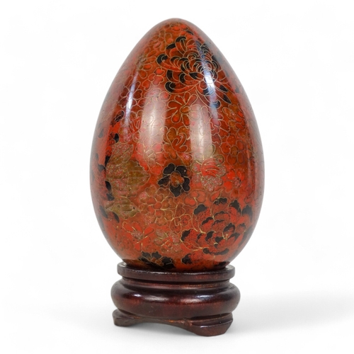 334 - A 20th century cloisonne egg - intensely decorated with flowers, raised on a hardwood stand, 20cm hi... 