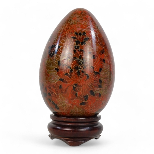 334 - A 20th century cloisonne egg - intensely decorated with flowers, raised on a hardwood stand, 20cm hi... 