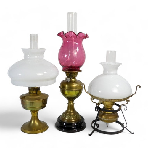 34 - A late 19th century brass oil lamp - with cranberry glass shade, raised on a stepped circular vitreo... 