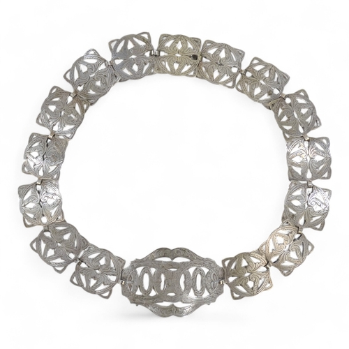 582 - An early 20th century silver plated belt - formed from interlinked pierced and foliate engraved squa... 