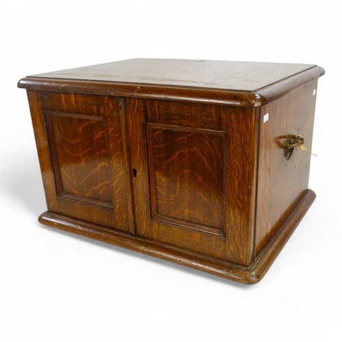 588 - An early 20th century oak canteen - the top incorporating a brass cartouche above a pair of panel do... 