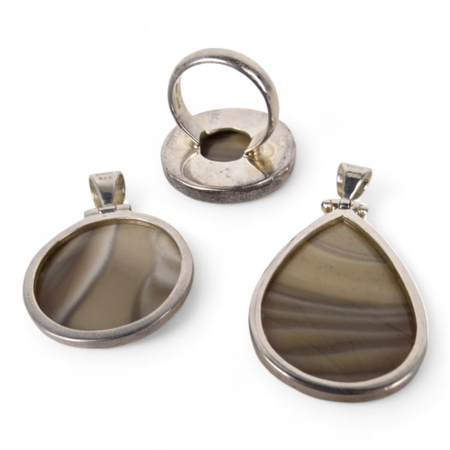 638 - A grey polished hardstone pendant - set within a silver mount, together with another and a similar r... 