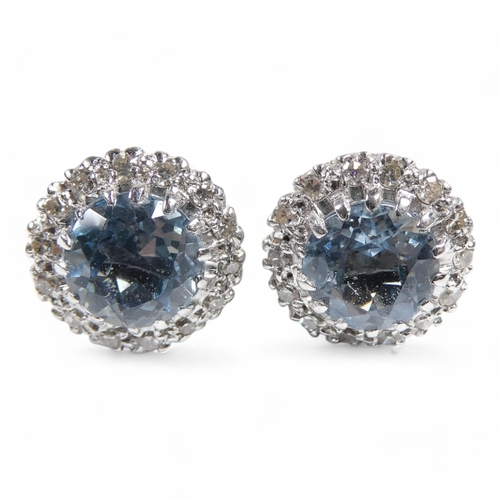 654 - A pair of aquamarine and diamond set ear studs - the central pale blue stones halo set within a band... 