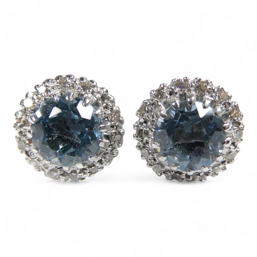 654 - A pair of aquamarine and diamond set ear studs - the central pale blue stones halo set within a band... 