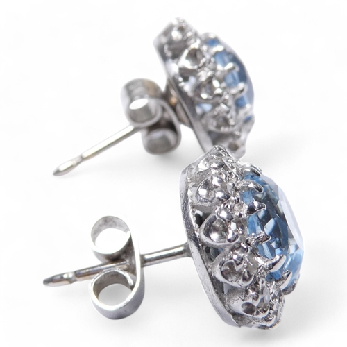 654 - A pair of aquamarine and diamond set ear studs - the central pale blue stones halo set within a band... 