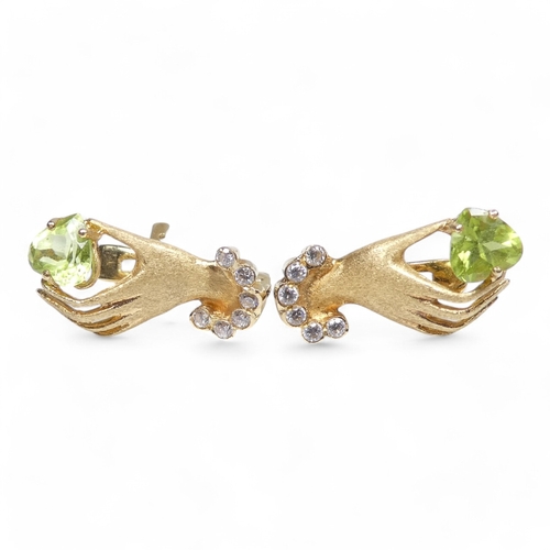 655 - A pair of 18ct gold and peridot set ear studs - modelled as a hand shape, the light green stones wit... 