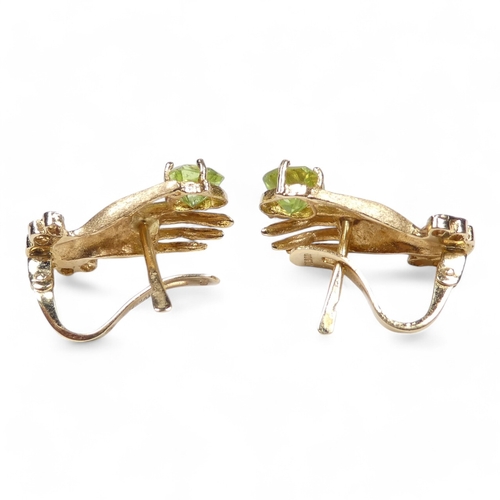 655 - A pair of 18ct gold and peridot set ear studs - modelled as a hand shape, the light green stones wit... 