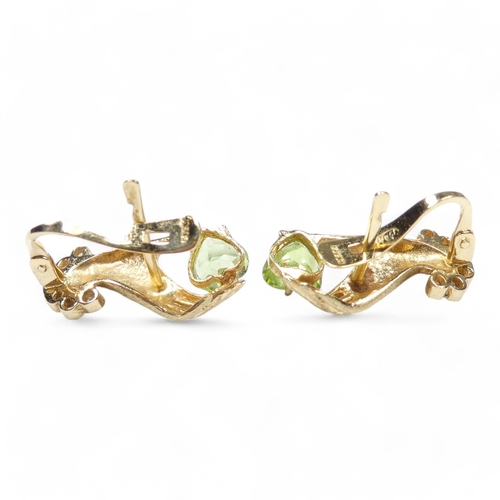 655 - A pair of 18ct gold and peridot set ear studs - modelled as a hand shape, the light green stones wit... 