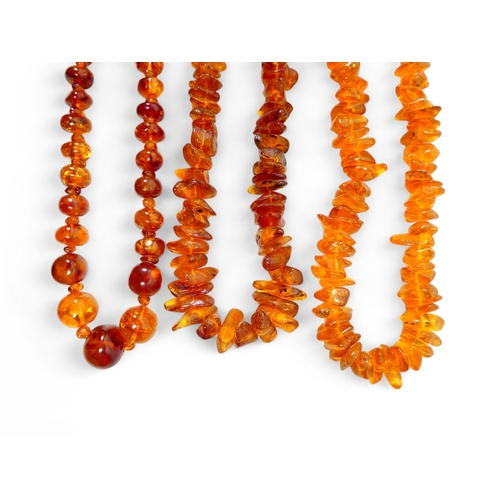 662 - A string of graduated asymmetrical amber beads - 68cm long, together with two further strings of amb... 