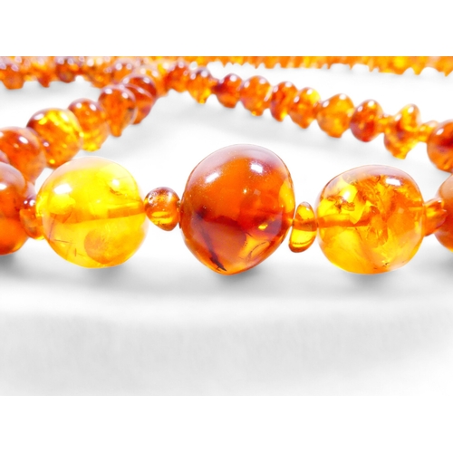 662 - A string of graduated asymmetrical amber beads - 68cm long, together with two further strings of amb... 