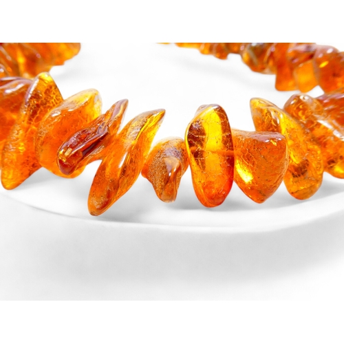 662 - A string of graduated asymmetrical amber beads - 68cm long, together with two further strings of amb... 