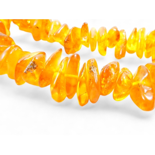 662 - A string of graduated asymmetrical amber beads - 68cm long, together with two further strings of amb... 