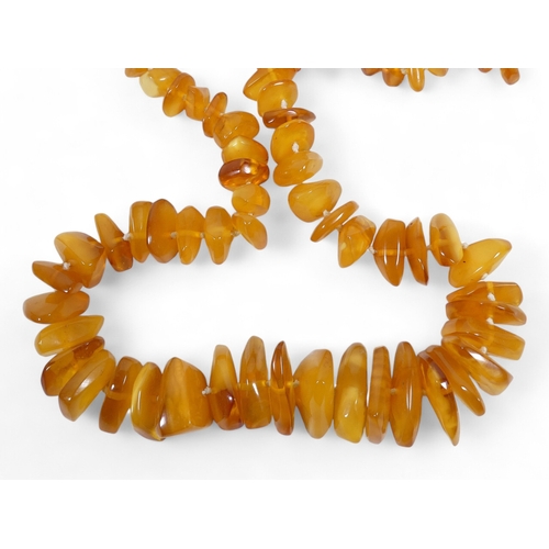 663 - A string of amber beads - of interspersed beads and disks, 44cm long, together with two further stri... 