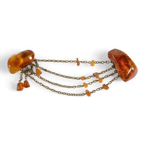 668 - An amber brooch - the two pieces linked by chains with amber drops, 32g.