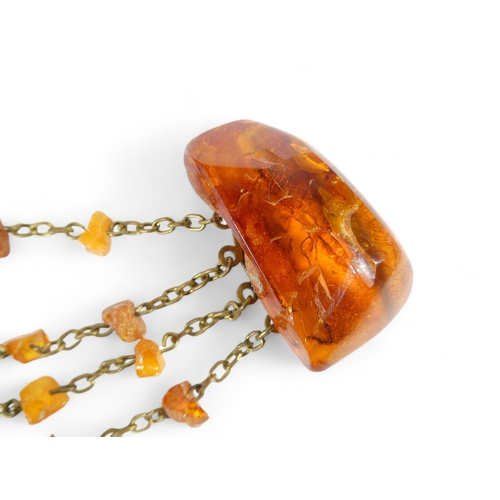 668 - An amber brooch - the two pieces linked by chains with amber drops, 32g.