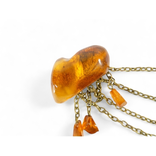 668 - An amber brooch - the two pieces linked by chains with amber drops, 32g.