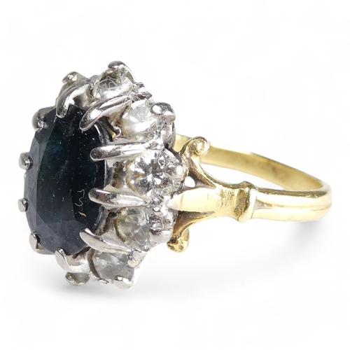 680 - A 9ct sapphire and diamond ring - the claw set oval central stone within a band of diamonds, size R,... 