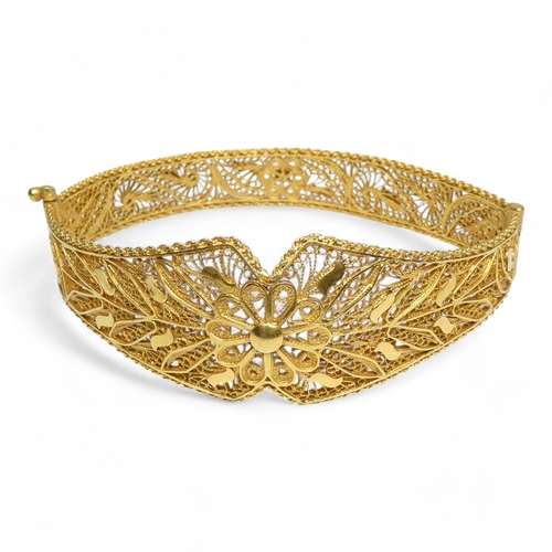 687 - A yellow metal filigree bangle - hinged and of foliate form, indistinctly marked, 24.7g.