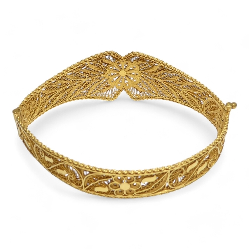 687 - A yellow metal filigree bangle - hinged and of foliate form, indistinctly marked, 24.7g.