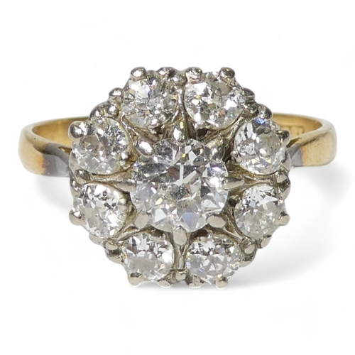 690 - An 18ct diamond cluster ring - with a central claw set stone, approx. 0.75ct, within a band of small... 