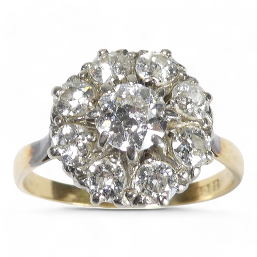 690 - An 18ct diamond cluster ring - with a central claw set stone, approx. 0.75ct, within a band of small... 