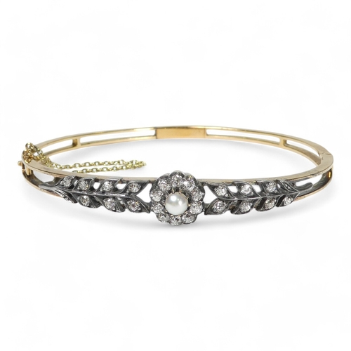 691 - A diamond and pearl set bangle - the claw set pearl within a band of diamonds flanked by foliage, 13... 