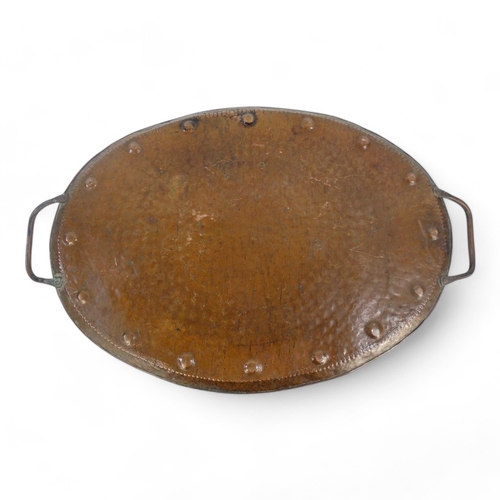 79 - John Pearson (British 1858-1930) a large oval copper tray - with a planished finish and domed border... 