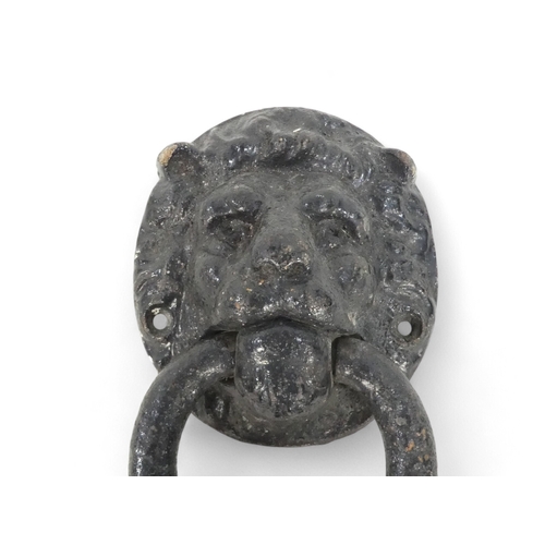 82 - A 19th century cast iron door knocker - modelled as a lion mask holding a ring, together with a butt... 