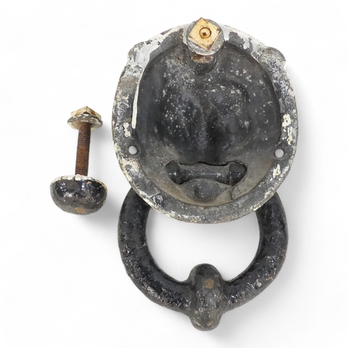 82 - A 19th century cast iron door knocker - modelled as a lion mask holding a ring, together with a butt... 