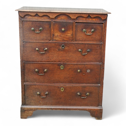 942 - A George III oak chest of drawers - the rectangular top with cusped corners above an arrangement of ... 