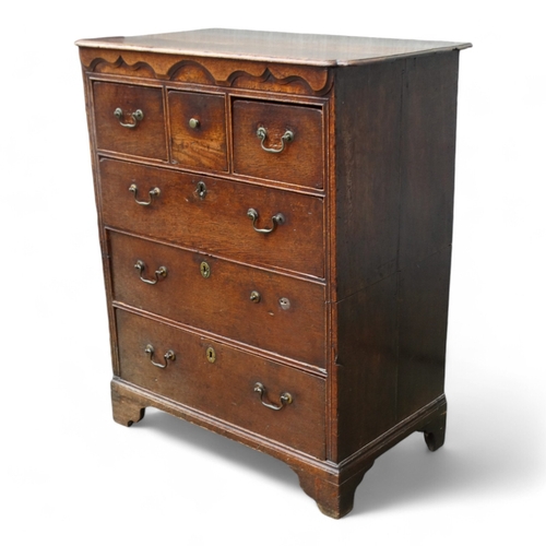 942 - A George III oak chest of drawers - the rectangular top with cusped corners above an arrangement of ... 