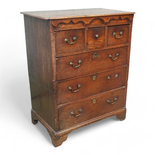 942 - A George III oak chest of drawers - the rectangular top with cusped corners above an arrangement of ... 