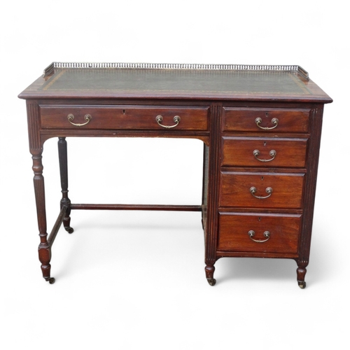 946 - An Edwardian mahogany desk - of asymmetrical form, the rectangular leather inset top with brass gall... 