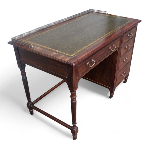 946 - An Edwardian mahogany desk - of asymmetrical form, the rectangular leather inset top with brass gall... 