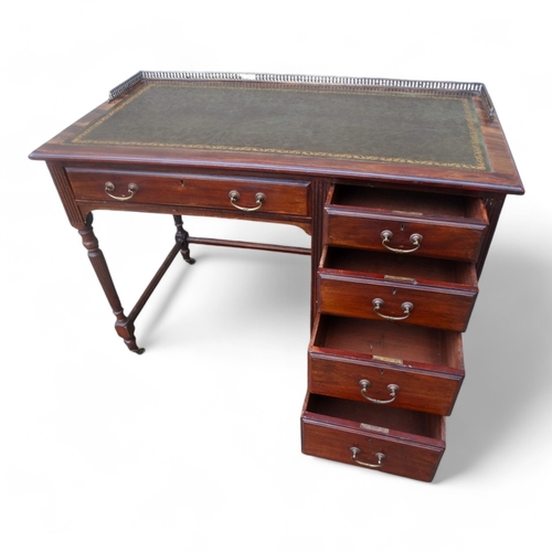 946 - An Edwardian mahogany desk - of asymmetrical form, the rectangular leather inset top with brass gall... 