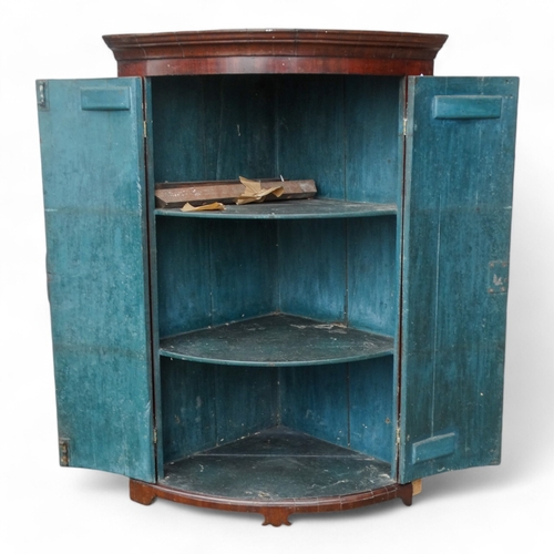 973 - A George III mahogany bowfront corner cupboard - the moulded cornice above a pair of doors enclosing... 