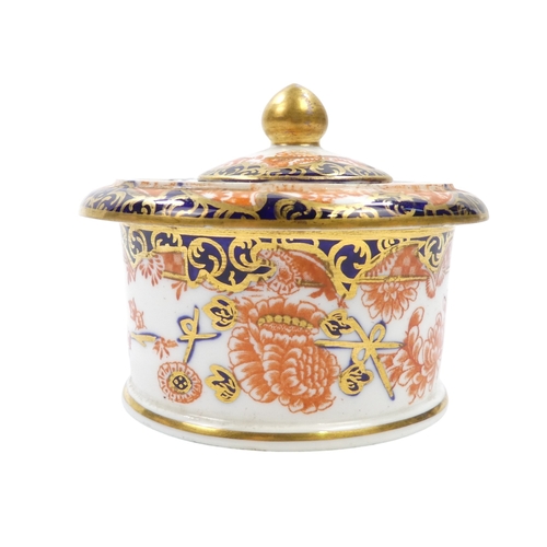 253 - A Royal Crown Derby inkwell - circular with cover and decorated in the Imari style, 8cm diameter, to... 