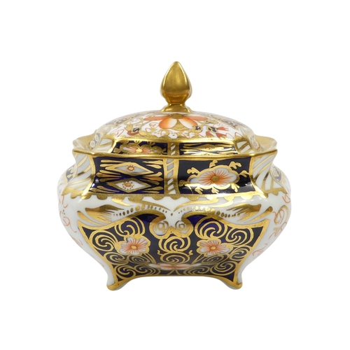 253 - A Royal Crown Derby inkwell - circular with cover and decorated in the Imari style, 8cm diameter, to... 