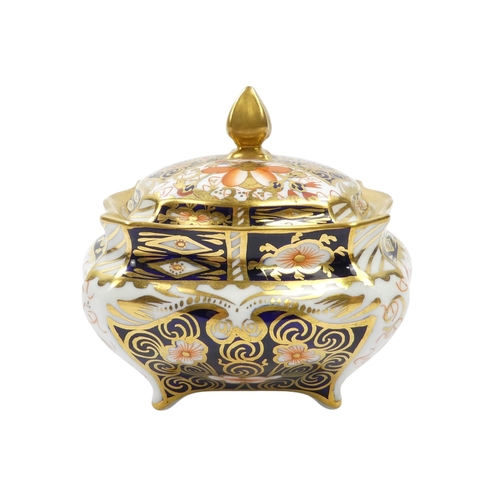 253 - A Royal Crown Derby inkwell - circular with cover and decorated in the Imari style, 8cm diameter, to... 