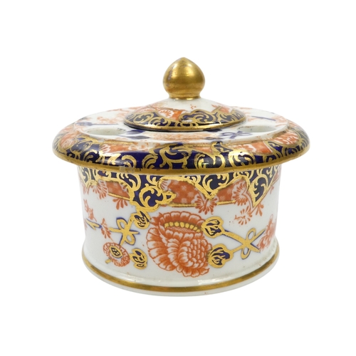 253 - A Royal Crown Derby inkwell - circular with cover and decorated in the Imari style, 8cm diameter, to... 