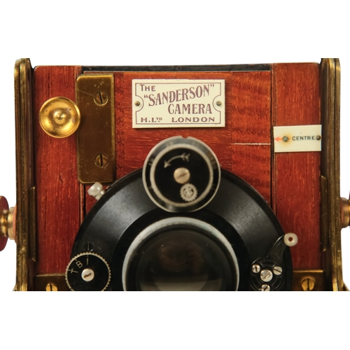 26 - A Sanderson deluxe field camera - the mahogany body with black resin cover, featuring red bellows fi... 