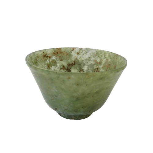 342 - A Chinese spinach jade bowl - with slightly overted rim and raised on a foot, 6cm diameter.