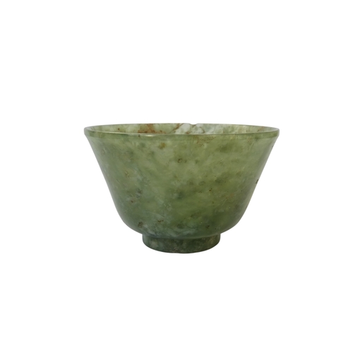 342 - A Chinese spinach jade bowl - with slightly overted rim and raised on a foot, 6cm diameter.