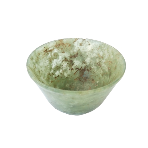 342 - A Chinese spinach jade bowl - with slightly overted rim and raised on a foot, 6cm diameter.