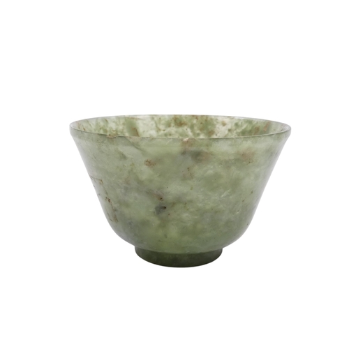 342 - A Chinese spinach jade bowl - with slightly overted rim and raised on a foot, 6cm diameter.