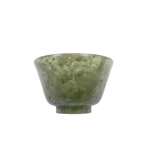 342 - A Chinese spinach jade bowl - with slightly overted rim and raised on a foot, 6cm diameter.