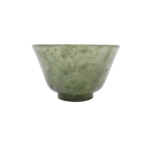 342 - A Chinese spinach jade bowl - with slightly overted rim and raised on a foot, 6cm diameter.