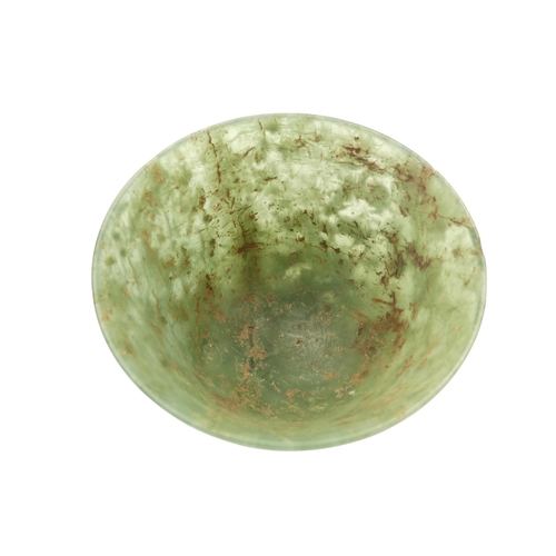 342 - A Chinese spinach jade bowl - with slightly overted rim and raised on a foot, 6cm diameter.