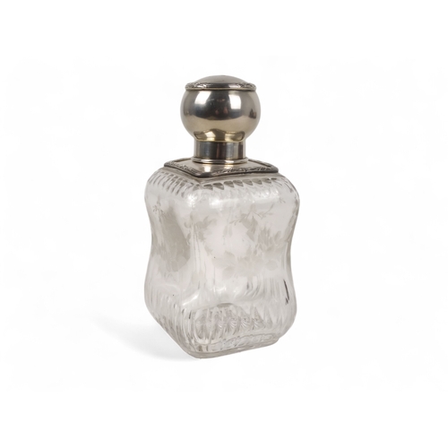 499 - A continental white metal mounted glass perfume bottle - square of a waisted form and etched with fl... 